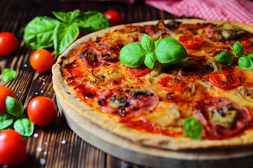 homemade pizza with ham, tomatoes and basil
