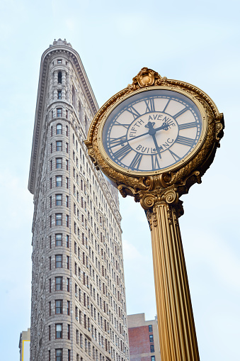 New York - September 10, 2016: Flatiron and Fifth Avenue building golden clock. Completed in 1902 was one of the tallest skyscraper in the city with his 20 floors.