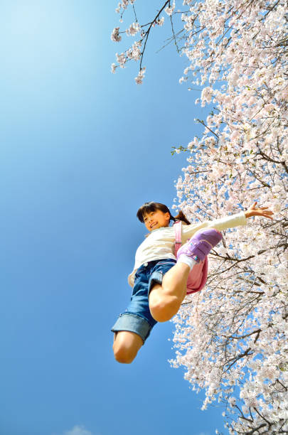 cherry blossoms and elementary school girls - arms outstretched teenage girls jumping flying imagens e fotografias de stock