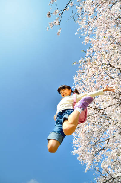 цветущая сакура и девочки начальной школы - arms outstretched teenage girls jumping flying стоковые фото и изображения