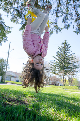 Little girl having fun while making the plane on a swing outside during a day of springtime