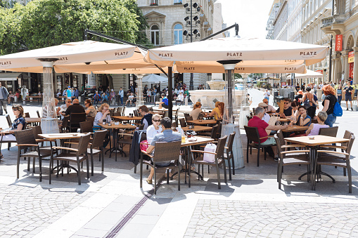 Tourists on the Summer cafe area in Budapest, Hungary. Budapest is the capital and most populous city of Hungary and one of the largest cities in the European Union. Budapest has a lot of attractions, Every year a lot of tourist visit Budapest.