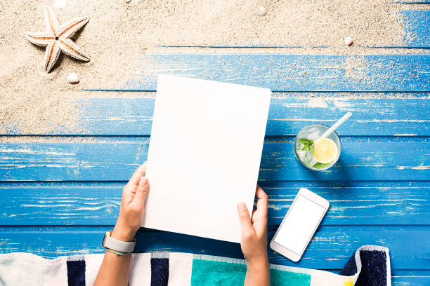 istock Woman hands holding white blank magazine on beach towel 816042388