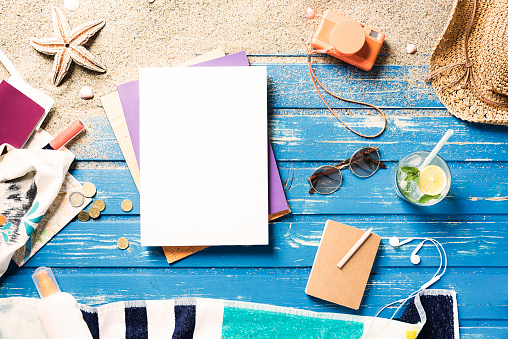 White blank magazine on blue wooden beach platform with summer accessories. Directly above shot.