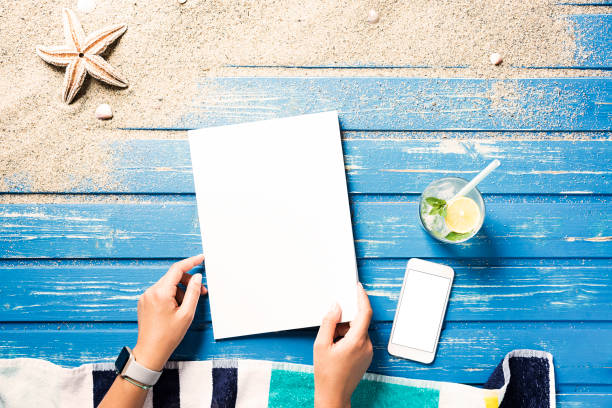 istock Woman hands holding white blank magazine on beach towel 816074136