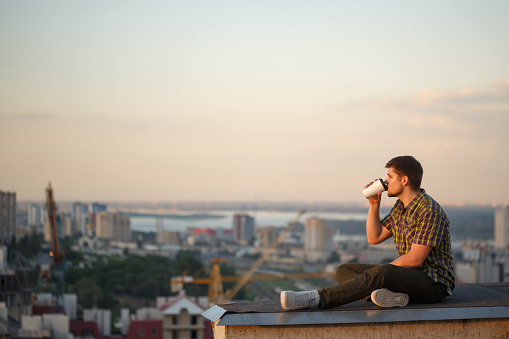 Man is drinking coffee on roof in morning