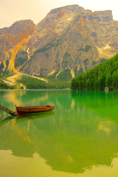 bateau en bois solitaire et lac alpin turquoise pragser (lago di braies), paysage idyllique près majestueuse vallée seekofel alpes, panorama spectaculaire de montagnes italiennes du sud tirol dolomites enneigées, italie - latemar mountain range photos et images de collection