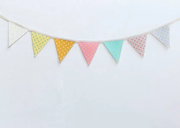 Design vintage fabric party flag over white cement wall texture background, outdoor day light