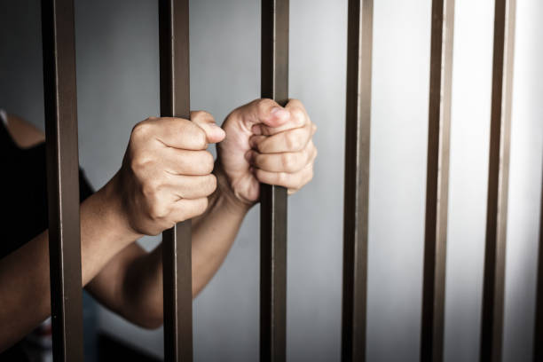 istock hands of woman behind jail bars. selective focus. 816129286