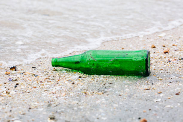 istock Green glass bottles were left on the beach. 816149514