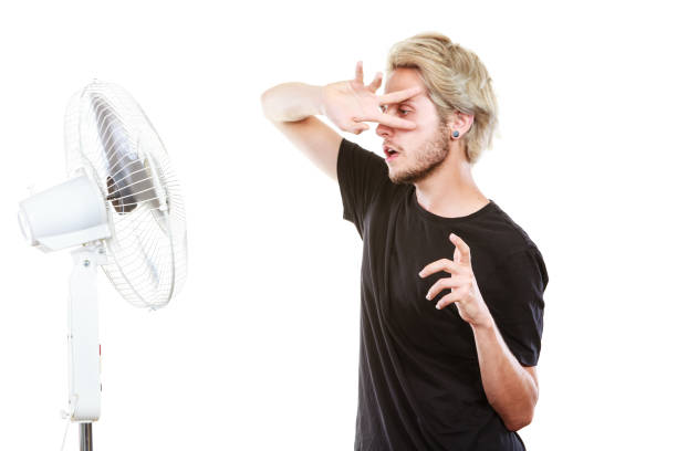 istock Young man fighting with wind from cooling fan 816159046