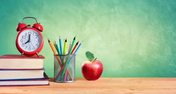 Photo of Alarm Clock And Stack Of Books With Pencils And Apple