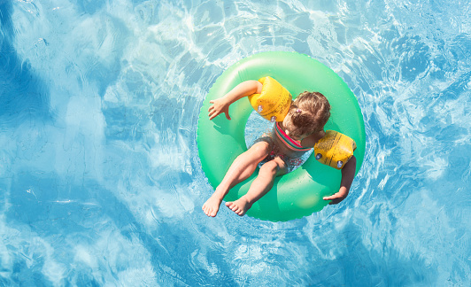 Happy girl floating on swim ring in the swimming pool