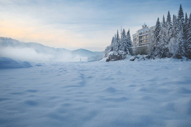 Castle on the River The hotel, which stands on the bank of a frozen river. In its windows reflect the light of the rising sun. Katun River, Mountain Altai, Siberia, Russia altai mountains photos stock pictures, royalty-free photos & images
