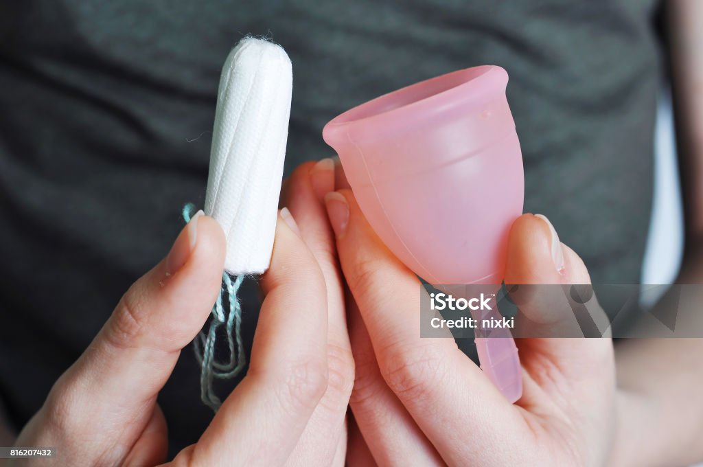 Junge Frau die Hände halten verschiedene Arten der Damenhygiene - Menstruationstasse und tampons - Lizenzfrei Menstruationstasse Stock-Foto
