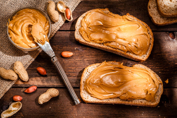 istock Peanut butter on bread slices shot on rustic wooden table 816233462