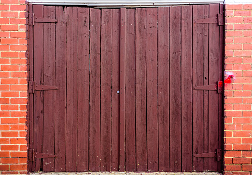 Red wood garage door with a red brick wall