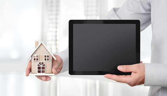 Hands with house and digital tablet, advertisement concept