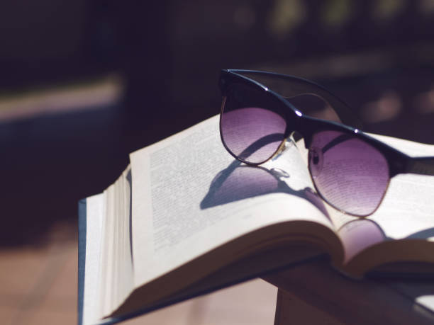 istock Old open book with sunglasses on a table outdoors. 816253796