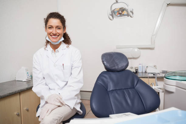 istock Dentist smiling at camera beside chair 816253822