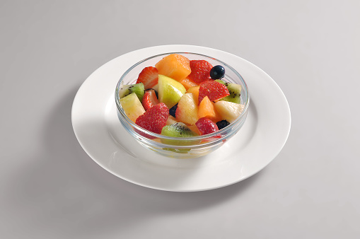 Bowl with a portion of mixed fruit salads isolated on grey background