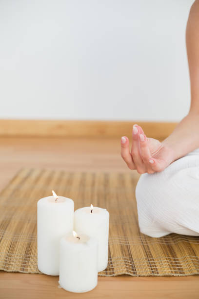 istock Woman sitting in lotus pose beside white candles 816273714