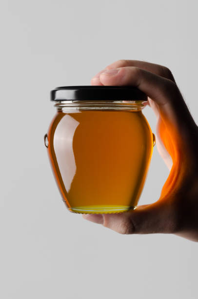 Honey Jar Mock-Up - Male hands holding a honey jar on a gray background