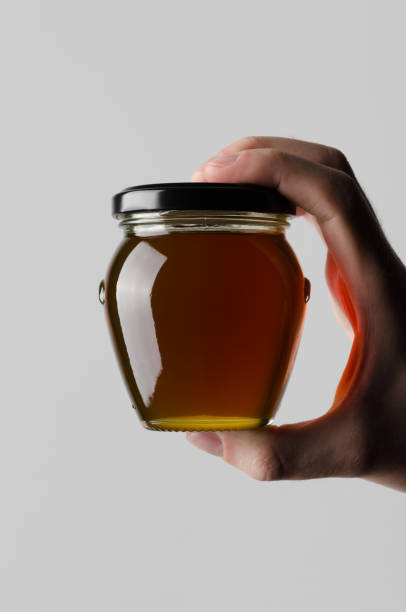 Honey Jar Mock-Up - Male hands holding a honey jar on a gray background
