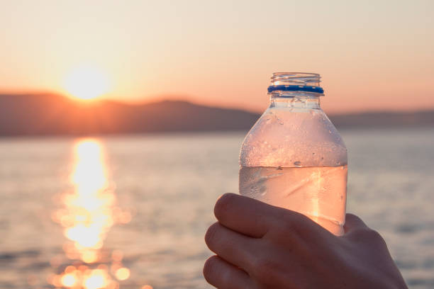 istock Man hold cold plastic bottle water on his hand at sunset 816290388