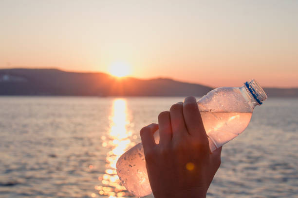 istock Man hold cold plastic bottle water on his hand at sunset 816290474