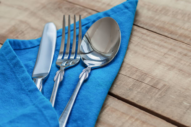 istock Silver tableware on blue napkin. Big spoon, fork and knife 816291600
