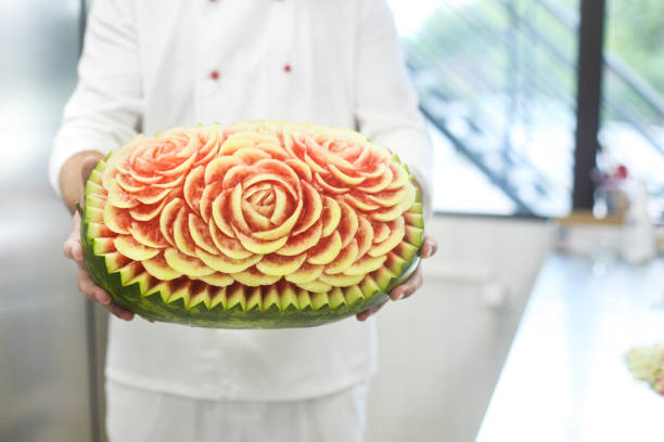 Chef holding a carved watermelon Chef holding a carved watermelon in kitchen. Unrecognizable person, Caucasian male. fruit carving stock pictures, royalty-free photos & images