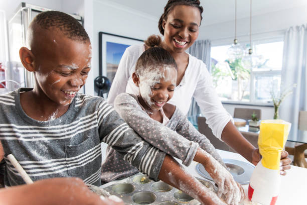 Parent baking muffins with her children. stock photo