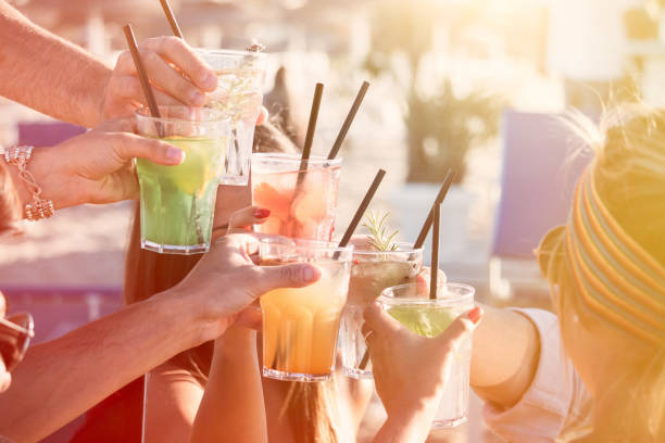 friends drinking cocktails close up hands with cocktails outdoor. group of friends party toasting with glasses. straw roof stock pictures, royalty-free photos & images