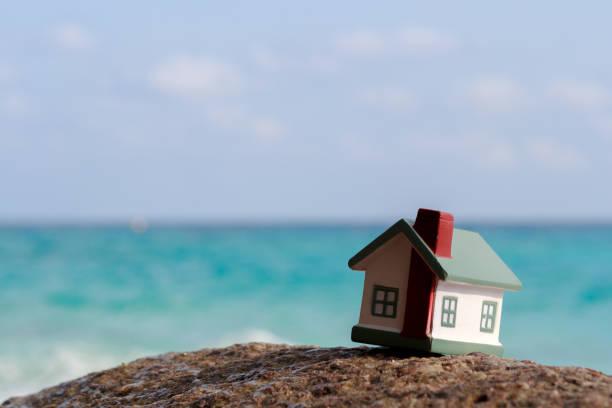 istock A toy house on a background of sea waves. Sandy beach. 816329366