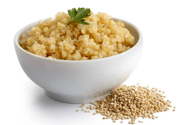 istock Cooked quinoa in white ceramic bowl isolated on white with green parsley. Spilled uncooked quinoa. 816342008