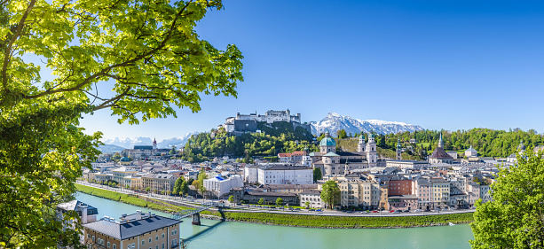 Hohensalzburg fortress seen from mount Kapuzinerberg, mountains snow covered, springtime, trees and bushes green and blooming