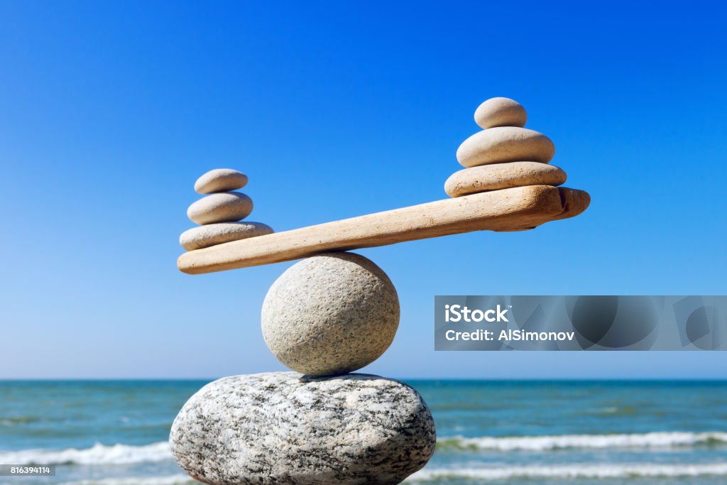 Concept of harmony and balance. Balance stones against the sea. Symbolic scales of stones on the background of the sea and blue sky. Concept of harmony and balance. Pros and cons concept Pros And Cons Stock Photo