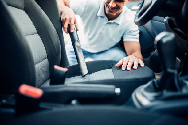istock Man cleans car interior with vacuum cleaner 816446128