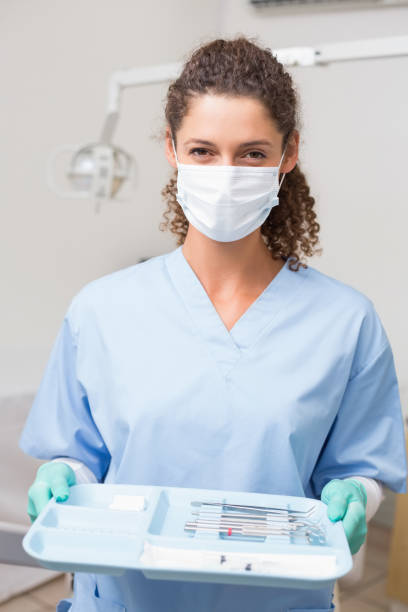 istock Dentist in blue scrubs holding tray of tools 816453028