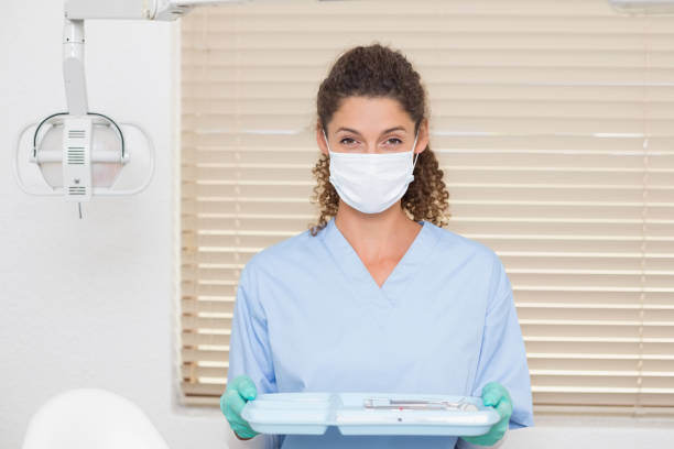istock Dentist in blue scrubs holding tray of tools 816453064