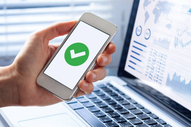 Smartphone with green checkmark on screen, validated, confirmed, completed, approved Hand holding a smartphone with a green checkmark icon on the screen to show a validated, confirmed, completed or approved status ok sign photos stock pictures, royalty-free photos & images