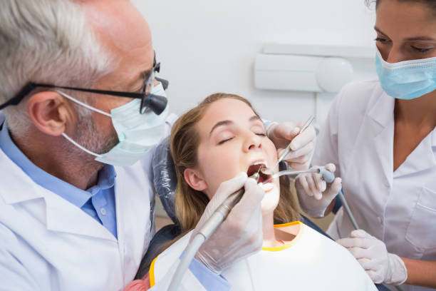 istock Dentist examining a patients teeth in the dentists chair with assistant 816466930