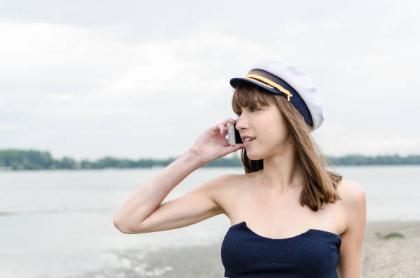 sailor woman holding mobile phone and talking or speaking, beautiful young girl on the beach with smart phone