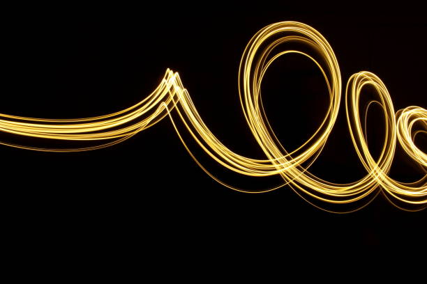 istock Gold Light Painting Photography, long exposure loops and waves pattern against a clean black background 816476890