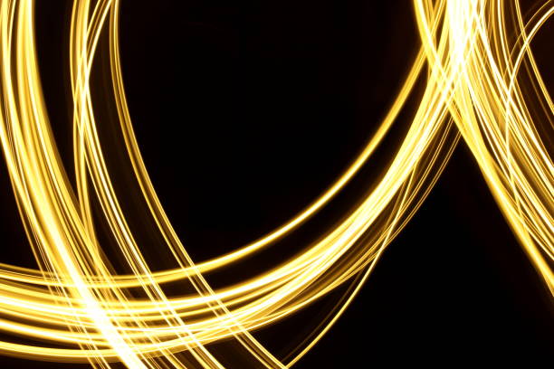 istock Gold Light Painting Photography, long exposure loops and waves pattern against a clean black background 816476896