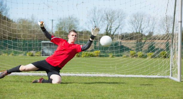 Goalkeeper in red ready to make a save Goalkeeper in red ready to make a save on a clear day teen goalie stock pictures, royalty-free photos & images