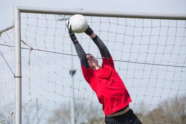 Goalkeeper in red jumping up to save a goal Goalkeeper in red jumping up to save a goal on a clear day teen goalie stock pictures, royalty-free photos & images