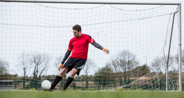 istock Goalkeeper in red kicking ball away from goal 816477574