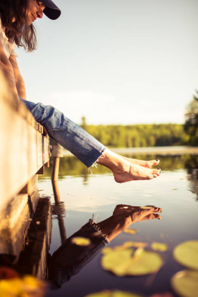 jovem mulher relaxa no cais do lago admirando os lírios de água - self reflection - fotografias e filmes do acervo